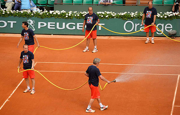 The Roland Garros grounds crew waters the court before the women's semifinals in 2013. (Bob Martin/SI)